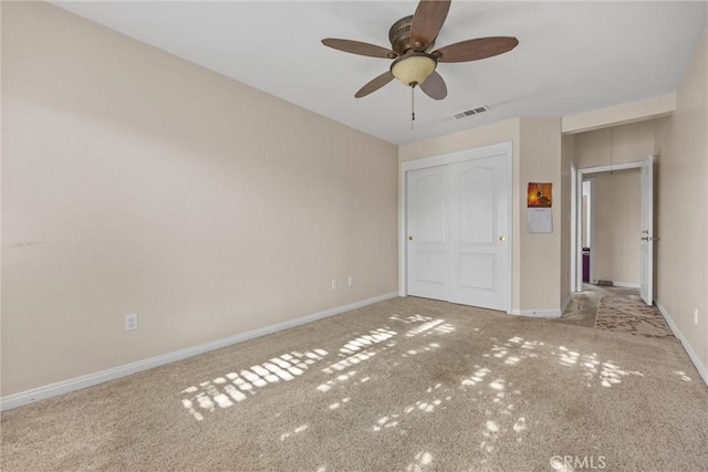 unfurnished bedroom with ceiling fan, light colored carpet, visible vents, baseboards, and a closet