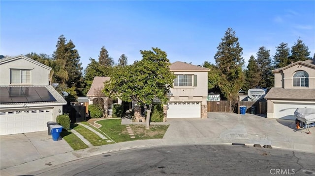 view of front of house featuring stucco siding, roof mounted solar panels, fence, a garage, and driveway