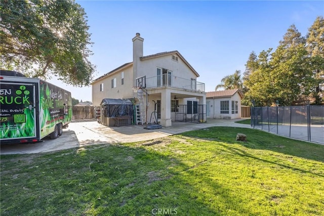 back of house with a patio, a chimney, stucco siding, a hot tub, and fence