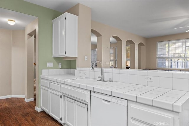 kitchen with baseboards, tile countertops, dark wood-type flooring, white dishwasher, and white cabinetry