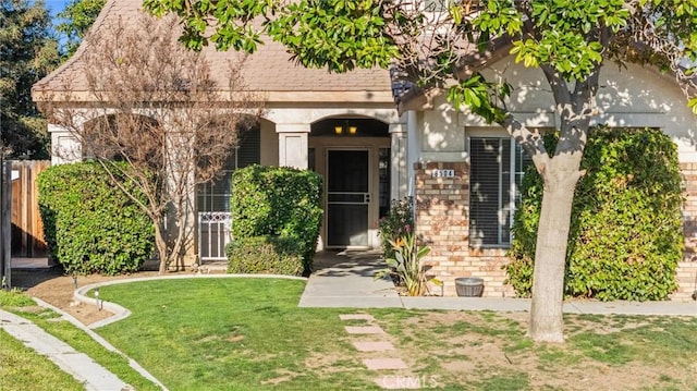 view of front of home featuring fence, a front lawn, and brick siding