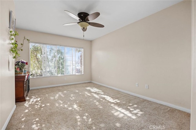 spare room featuring light carpet, ceiling fan, and baseboards