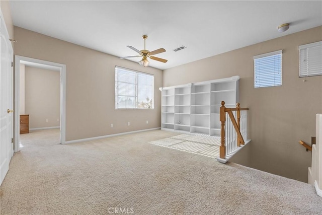 spare room with baseboards, visible vents, a ceiling fan, and light colored carpet