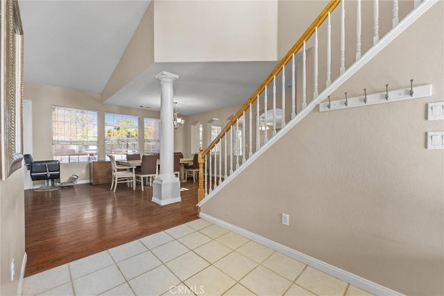 foyer entrance featuring a chandelier, light tile patterned flooring, a high ceiling, stairway, and decorative columns