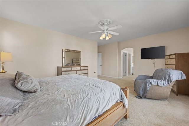 bedroom with arched walkways, a ceiling fan, and light colored carpet