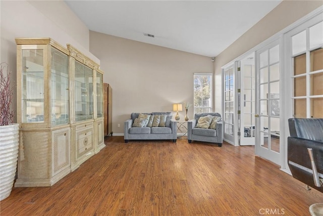 unfurnished room with baseboards, visible vents, lofted ceiling, wood finished floors, and french doors