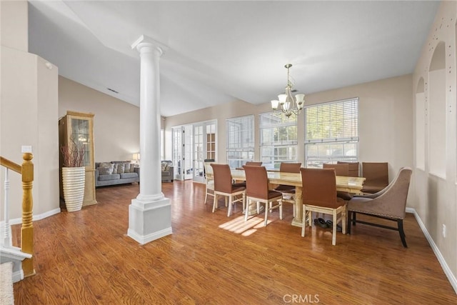 dining area with wood finished floors, stairs, vaulted ceiling, ornate columns, and a chandelier