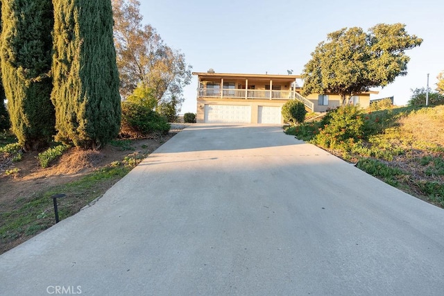 view of front of property with a garage, covered porch, stairs, and concrete driveway