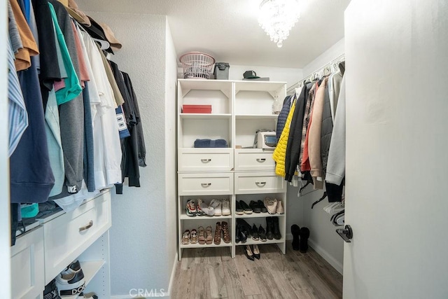 spacious closet with a chandelier and light wood finished floors