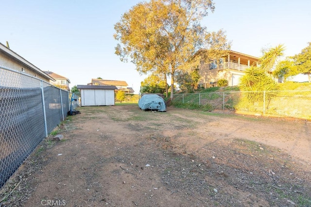 view of yard featuring a storage shed, fence, and an outbuilding