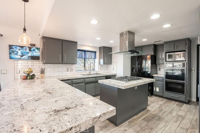 kitchen featuring a kitchen island, hanging light fixtures, island exhaust hood, black appliances, and a sink