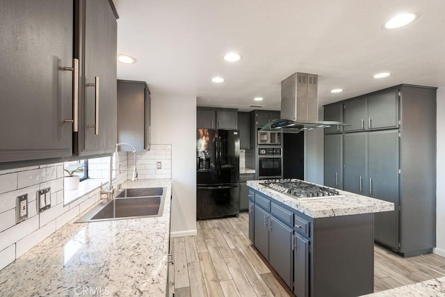 kitchen with light wood-style flooring, island range hood, a sink, a kitchen island, and black appliances