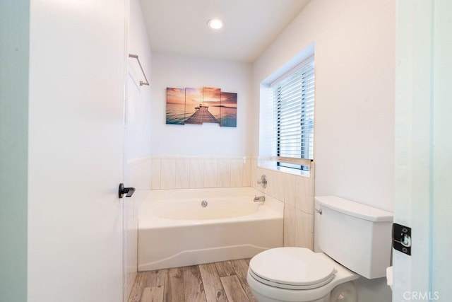 bathroom featuring a garden tub, toilet, and wood finished floors