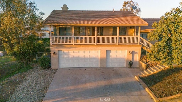 view of front of home featuring a tile roof, a chimney, stucco siding, concrete driveway, and an attached garage