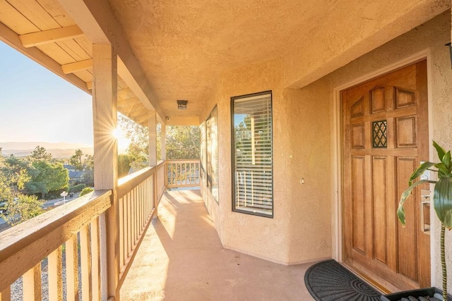 exterior entry at dusk featuring a balcony and stucco siding