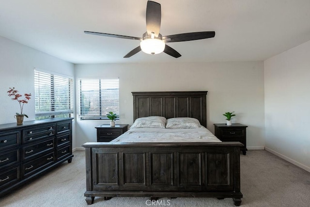 bedroom with a ceiling fan, light colored carpet, and baseboards