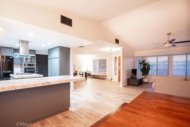 kitchen with island exhaust hood, light countertops, visible vents, open floor plan, and black appliances