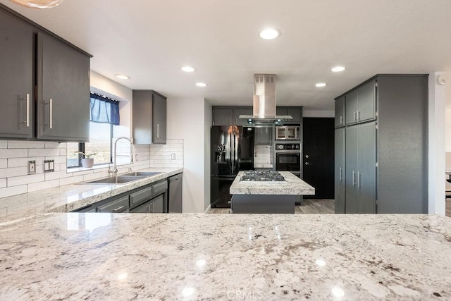 kitchen with backsplash, gray cabinetry, a sink, island range hood, and black appliances