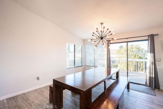 unfurnished dining area featuring light wood-type flooring, an inviting chandelier, baseboards, and lofted ceiling