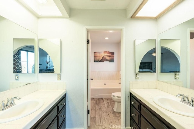 full bath featuring wood finished floors, a sink, toilet, and a bath