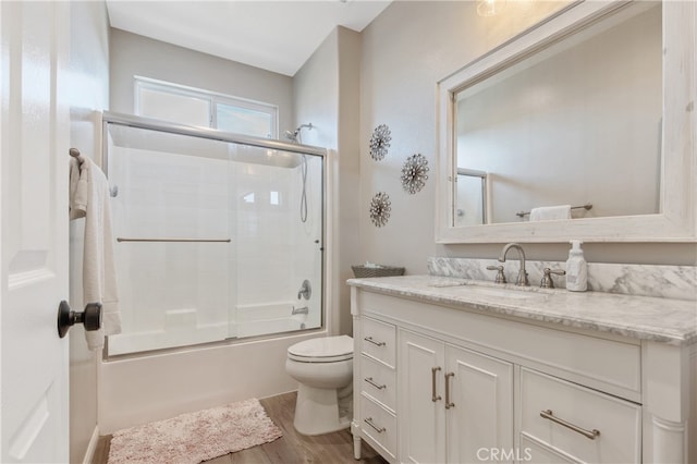 full bath with toilet, combined bath / shower with glass door, wood finished floors, and vanity