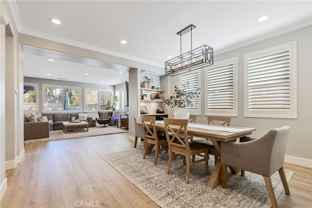 dining area featuring light wood-style flooring, recessed lighting, a notable chandelier, baseboards, and crown molding