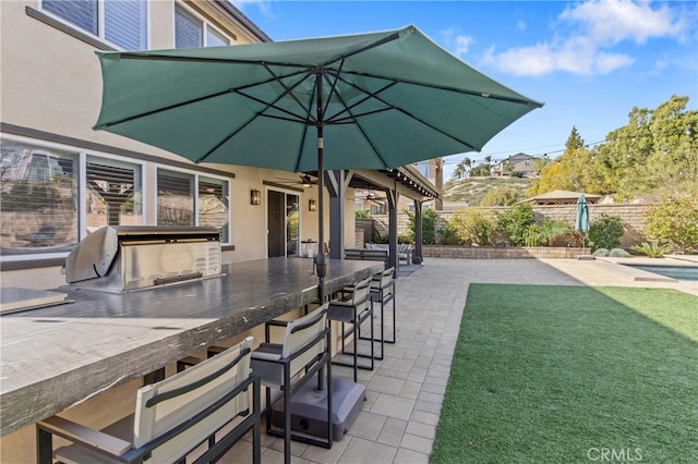 view of patio with outdoor wet bar, ceiling fan, area for grilling, and fence