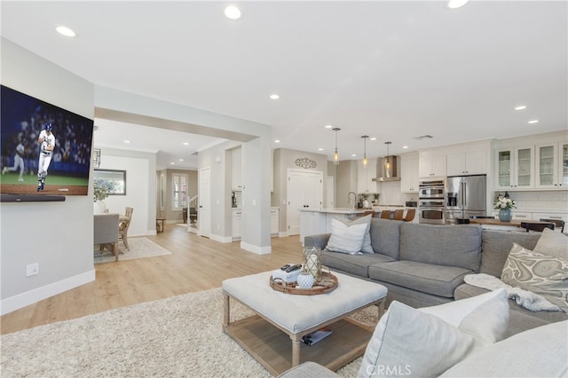 living area featuring recessed lighting, baseboards, and light wood finished floors