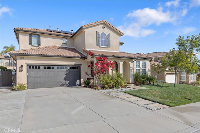 mediterranean / spanish house with a tiled roof, stucco siding, driveway, and roof mounted solar panels