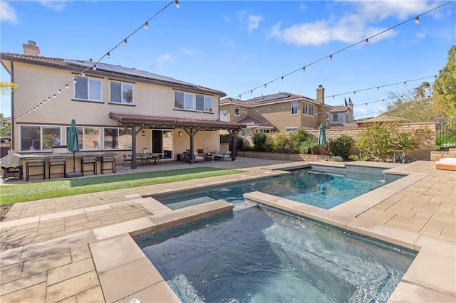 back of property featuring a patio area, fence, exterior bar, an in ground hot tub, and an outdoor pool