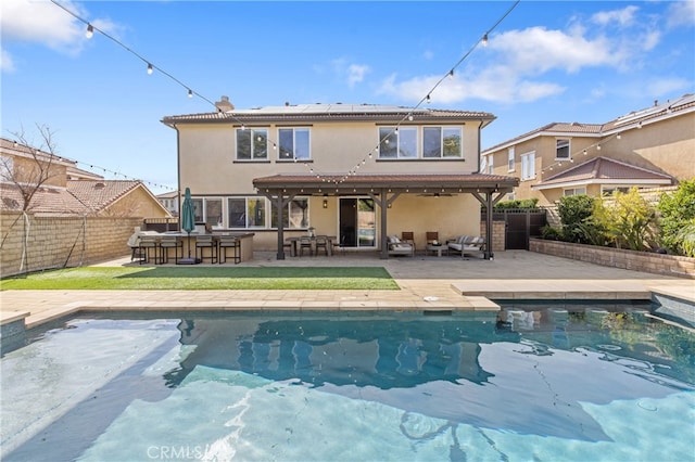 rear view of property featuring a fenced backyard, a patio, outdoor dry bar, and stucco siding