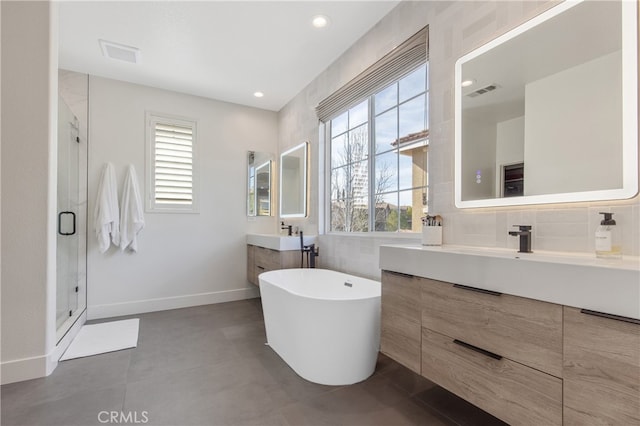 full bathroom featuring a stall shower, visible vents, two vanities, and a sink