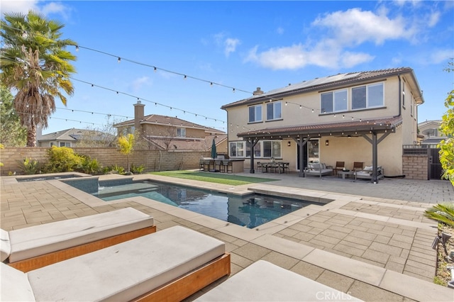 rear view of house with a fenced in pool, a fenced backyard, an in ground hot tub, a patio area, and stucco siding