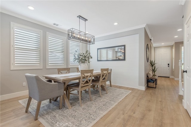 dining area with light wood-style floors, visible vents, crown molding, and baseboards