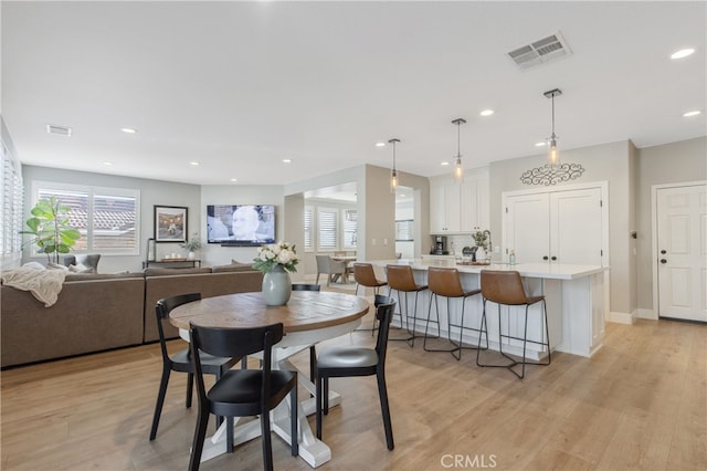 dining room with baseboards, light wood finished floors, visible vents, and recessed lighting