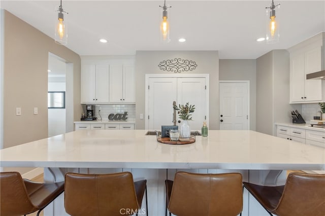 kitchen featuring hanging light fixtures, a large island, tasteful backsplash, and white cabinets