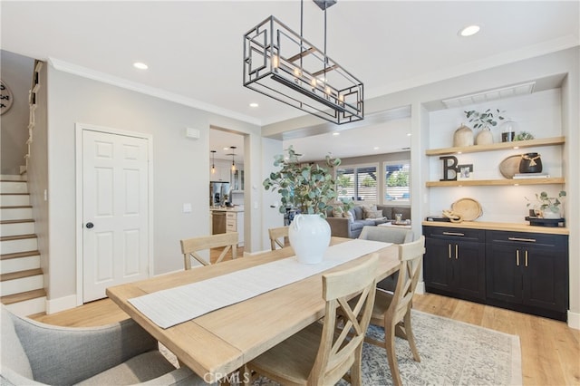 dining area featuring recessed lighting, crown molding, light wood finished floors, and stairs