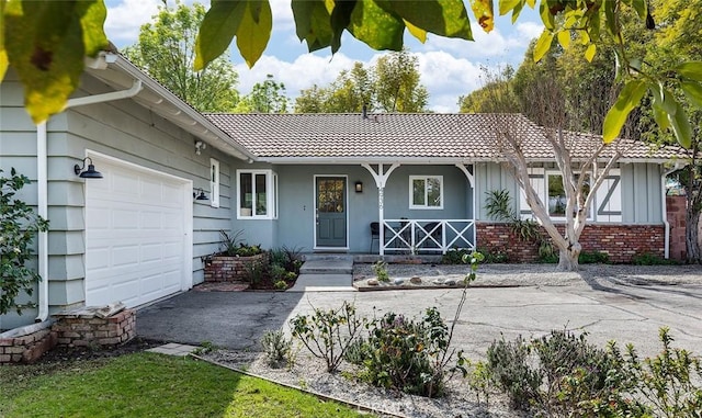 exterior space with brick siding, covered porch, an attached garage, driveway, and a tiled roof