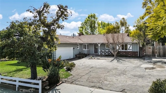 single story home featuring brick siding, an attached garage, a front yard, fence, and a tiled roof