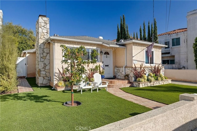 view of front of house featuring a front yard, fence, a chimney, and stucco siding