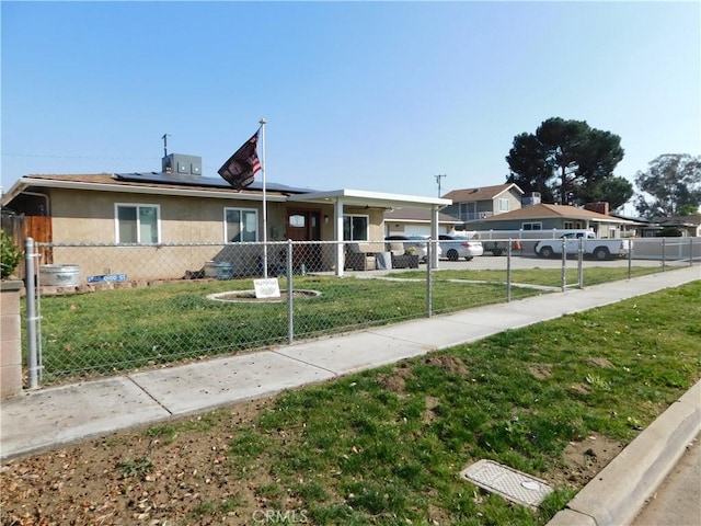 view of front of property featuring fence private yard, driveway, roof mounted solar panels, stucco siding, and a front lawn