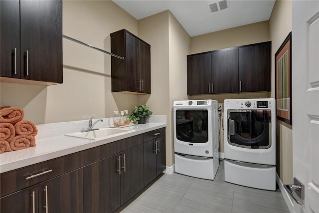 laundry area featuring washer and dryer, cabinet space, a sink, and visible vents