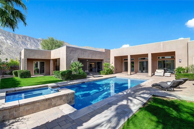 outdoor pool featuring a patio, a yard, a mountain view, and an in ground hot tub