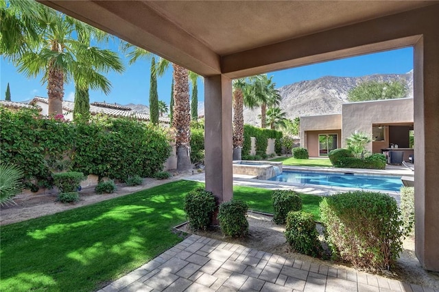 view of pool featuring a pool with connected hot tub, a patio area, a mountain view, and a lawn