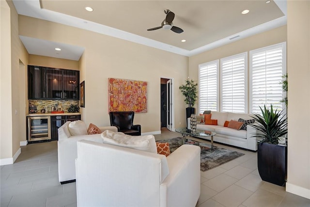 living room with beverage cooler, indoor wet bar, baseboards, and light tile patterned flooring