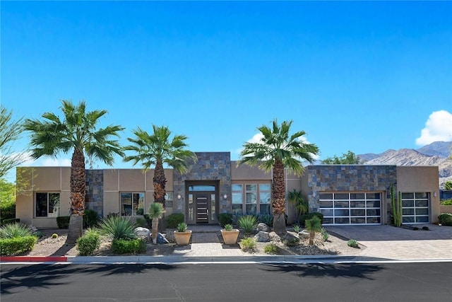 view of property featuring decorative driveway, a mountain view, and an attached garage