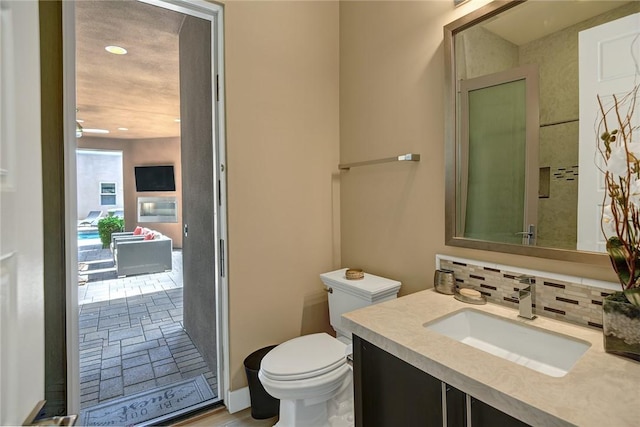 bathroom with backsplash, toilet, and vanity