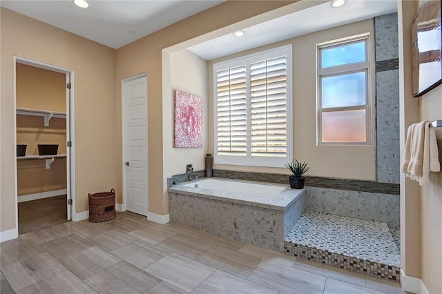 full bathroom with baseboards, a garden tub, a walk in closet, and recessed lighting
