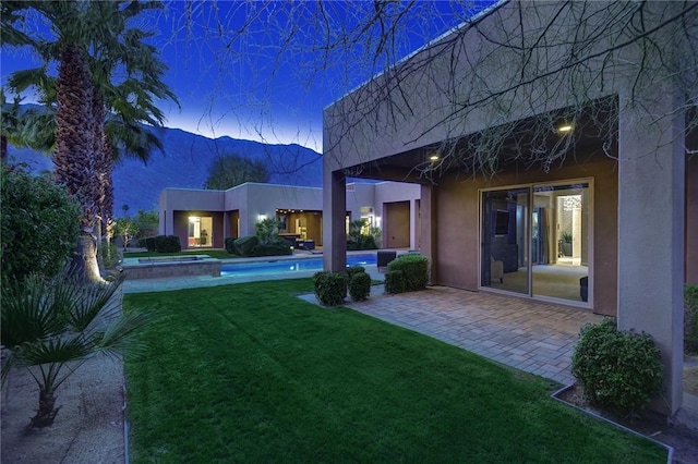 yard at dusk with a patio area, a mountain view, and an outdoor pool