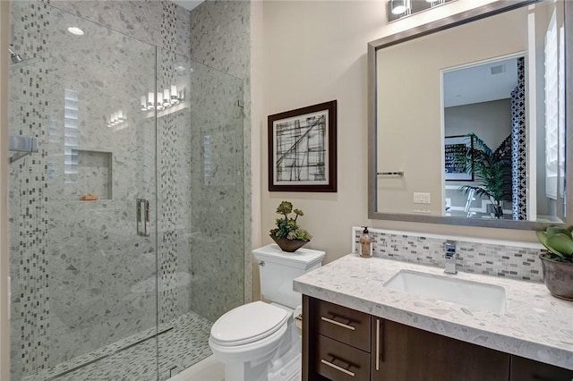 full bath with vanity, tasteful backsplash, a shower stall, and toilet